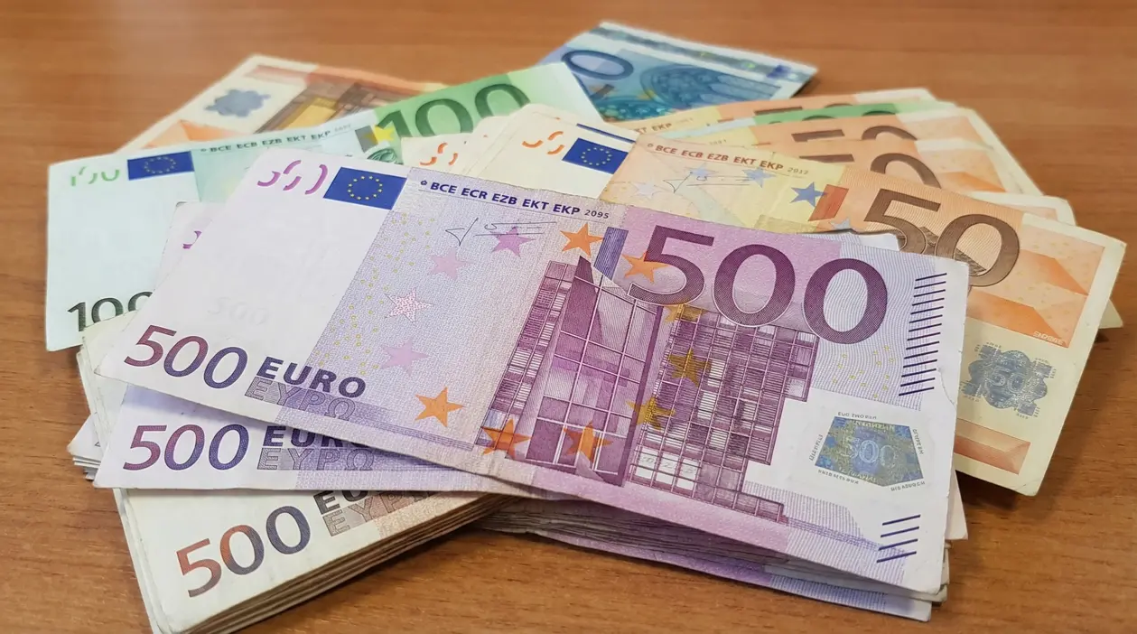 Mazzi di banconote in euro di vari tagli su un tavolo in legno