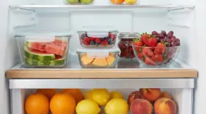 Frutta fresca conservata in contenitori di vetro all'interno di un frigorifero aperto